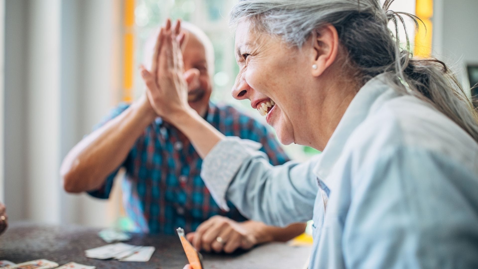 Dois idosos sorrindo enquanto jogam juntos em uma sala iluminada