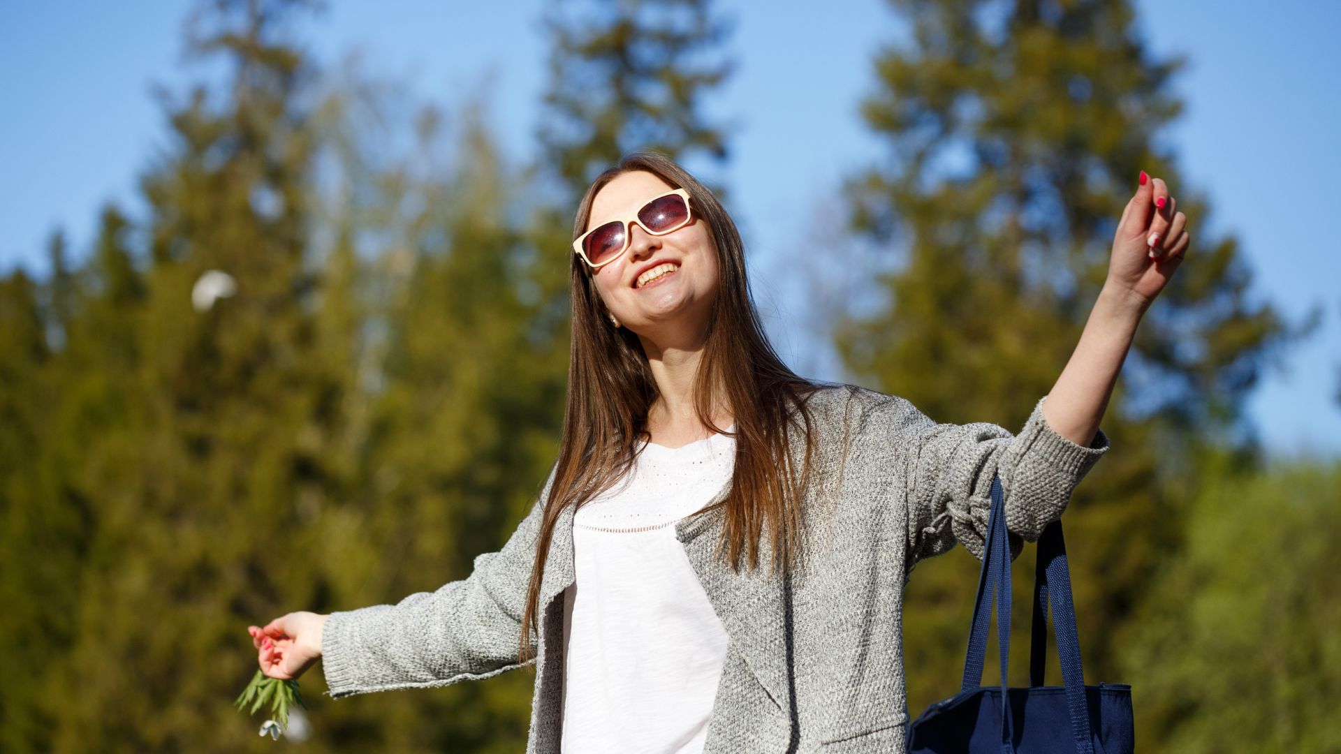 Mulher sorridente com os braços erguidos ao ar livre, expressando liberdade e bem-estar